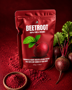 A stand-up pouch of beetroot powder or beetroot mix placed on a dark red surface, with whole beetroots, green leaves, and a small bowl of loose powder arranged around it. The pouch has a metallic deep red finish, white text reading 'BEETROOT - 100% PURE & ORGANIC,' and a beetroot illustration with green leaves on the front.