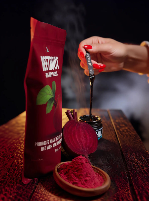 Red packet of beetroot powder with a hand scooping powder onto a wooden surface.